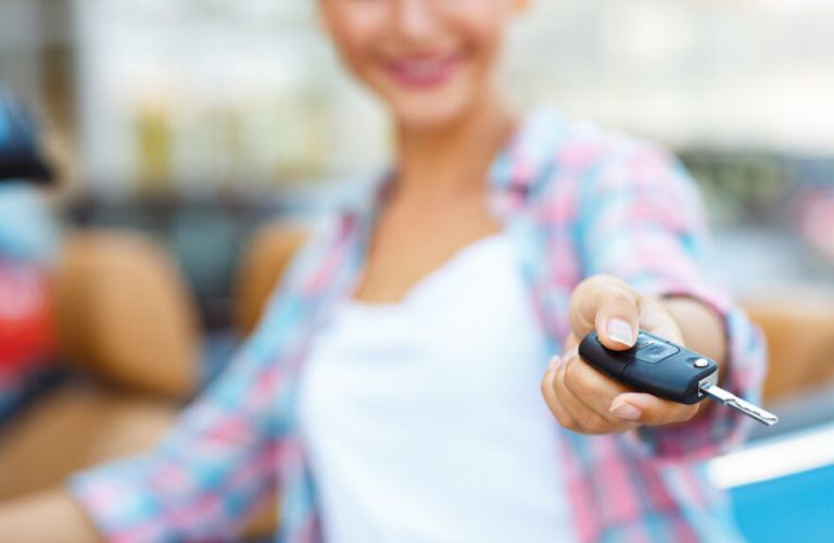 A woman holding the key to a car